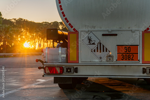 Camion cisterna de mercancias peligrosas con el sol de frente amaneciendo