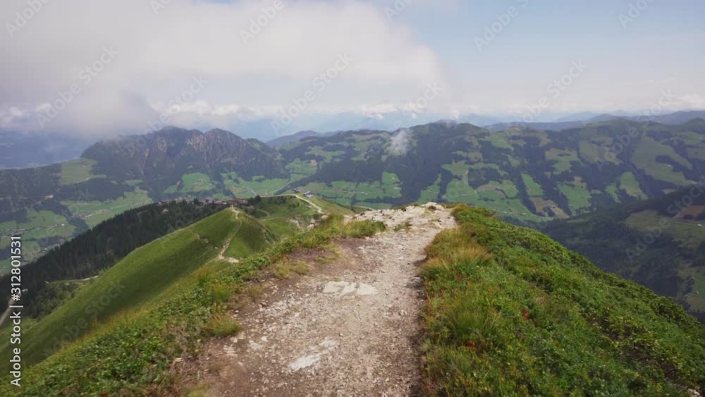 Climbing down from the peak of the mountain, nearby mountains surrounding it. Small trail leading down into the Alpbach Valley in Tirol. Climbing down from the peak of the mountain, nearby mountains surrounding it. Small trail leading down into the Alpbach Valley in Tirol.
