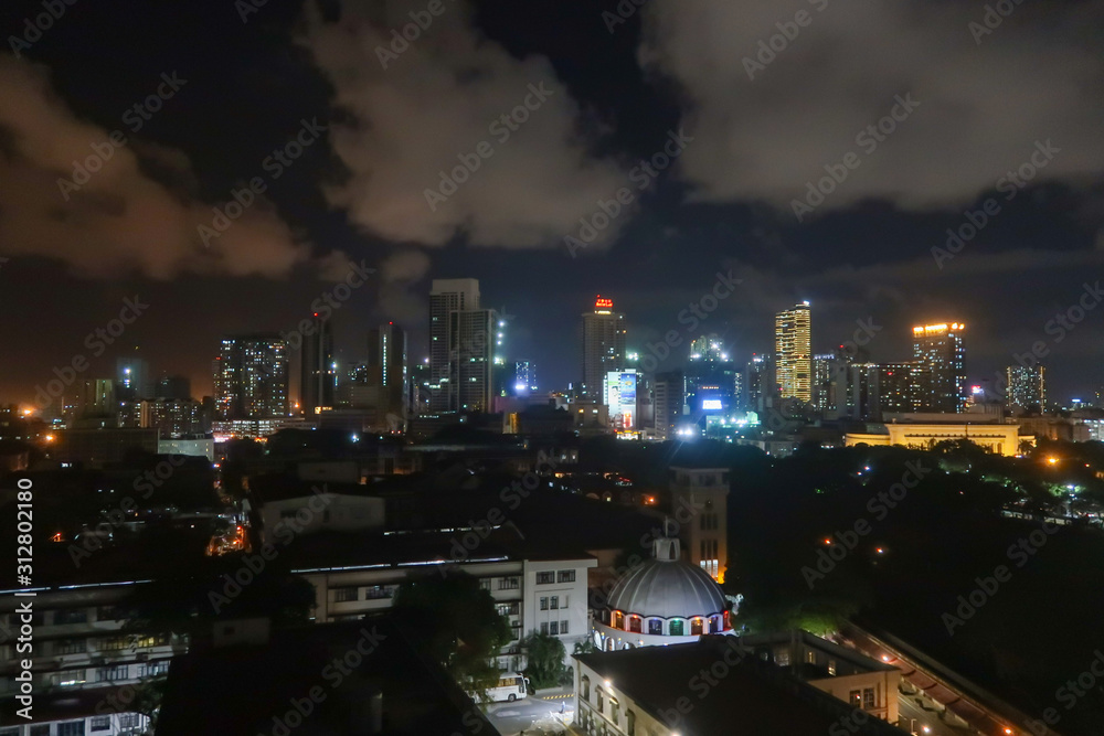 Manila Skyline At Night From Above At A Rooftop Restaurant Looking At The City, Palm Trees and Churches at Night