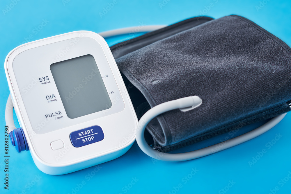 Digital blood pressure monitor on a blue background, closeup. Helathcare and medical concept Digital blood pressure monitor on a blue background, closeup. Helathcare and medical concept