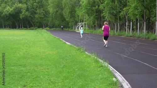 Mom and little daughter are running in the stadium. The concept of a healthy family. The family does fitness at the stadium. 4k footage.