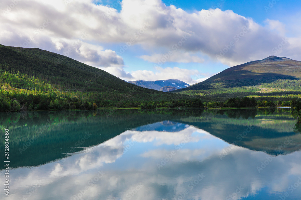 Reflection of mountains and clouds on still alpine lake