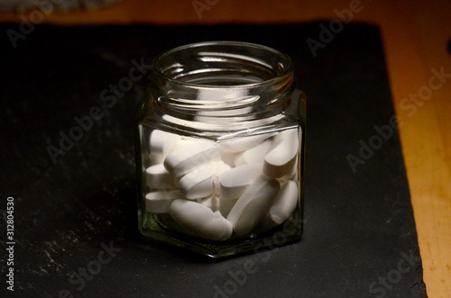 oblong white pills in glass hexagonal jar