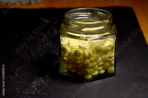small round yellow pills in clear glass hexagonal jar