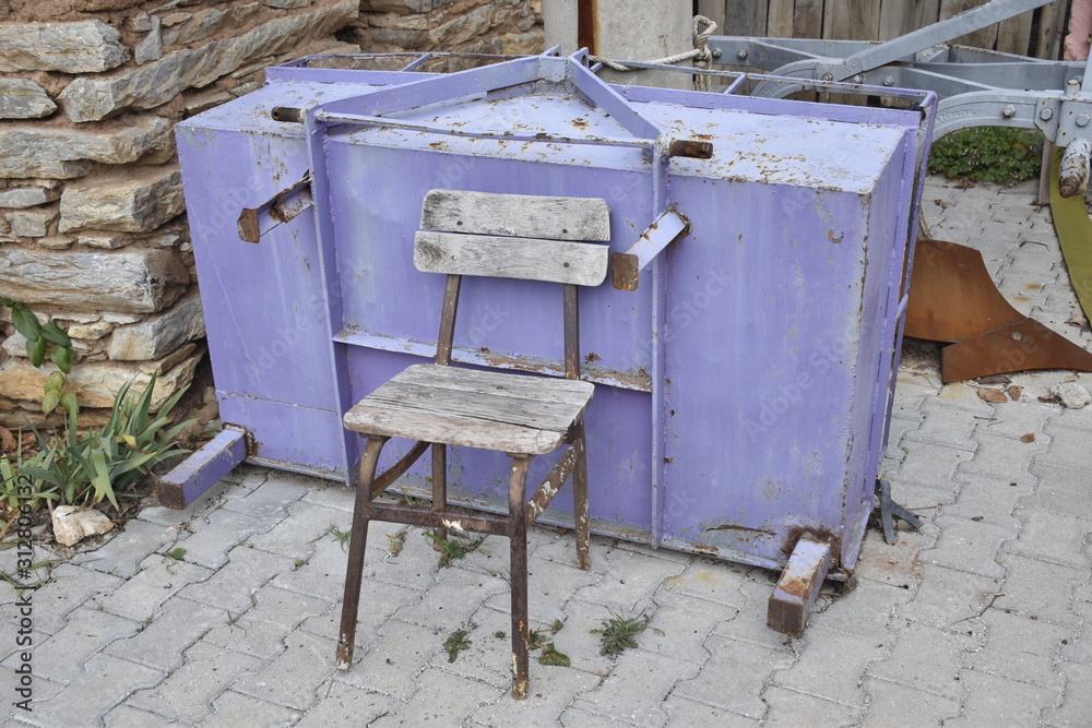 an agricultural tool and an old chair in front an agricultural tool and an old chair in front