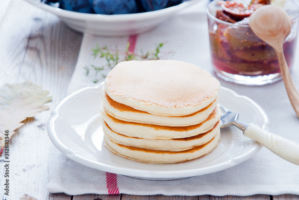 A stack of homemade pancakes with fig jam on a white plate A stack of homemade pancakes with fig jam on a white plate