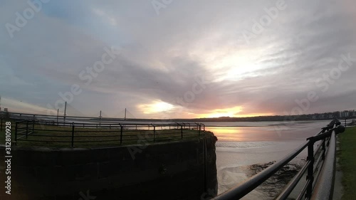 Sunrise waterfront river Mersey canal channel timelapse clouds passing fast overhead. photo