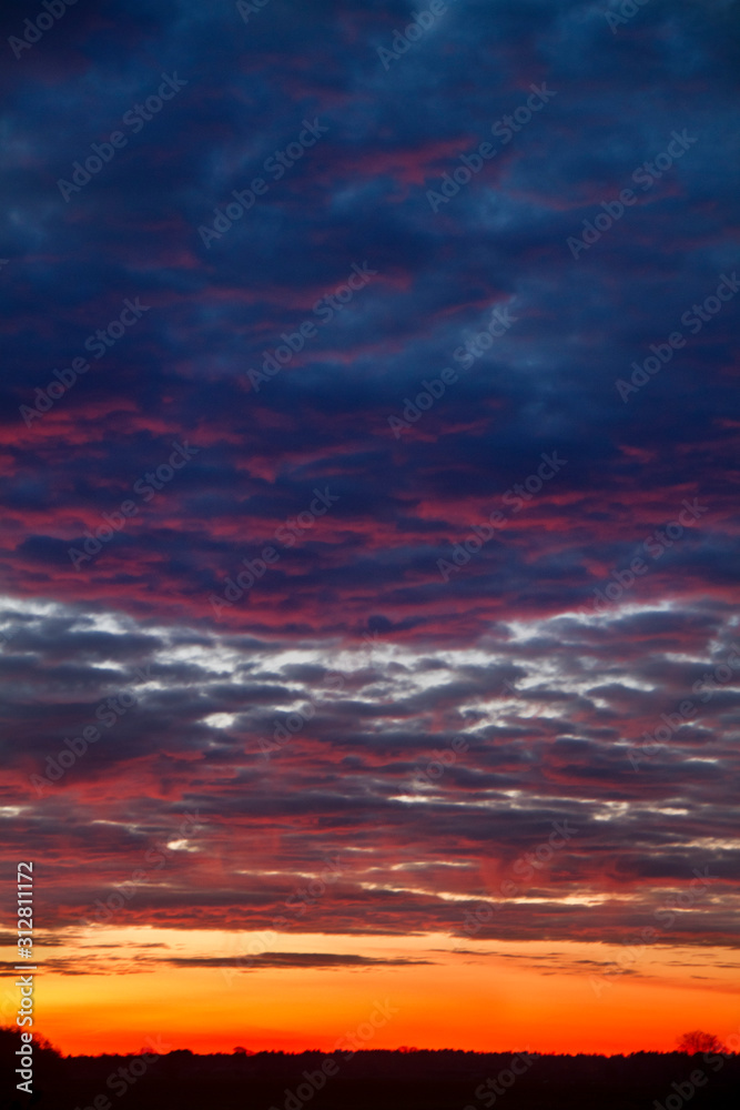 Beautiful sunrise: orange, red and dark blue clouds over a black horizon