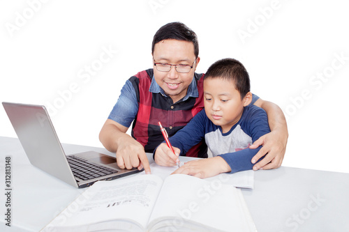 Asian man guiding his son doing his homework