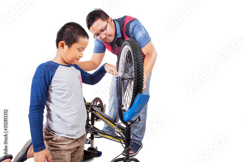 Asian man guiding his son how to fix his bike