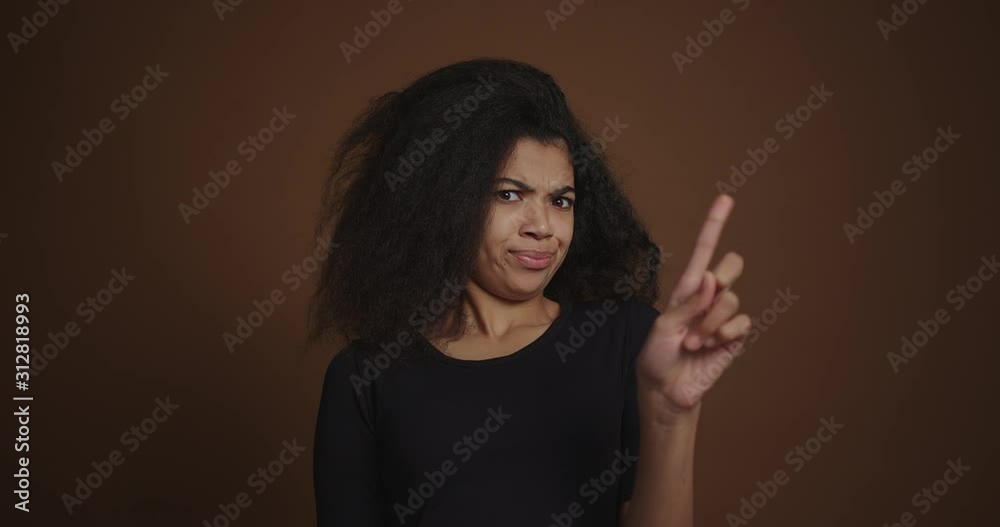 Portrait of african girl disapproving of finger gesture against brown wall Portrait of african girl disapproving of finger gesture against brown wall