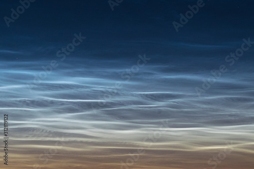 Close up of NLC: noctilucent clouds. Beautiful waves and ripples of silvery blue night shining clouds around midnight.