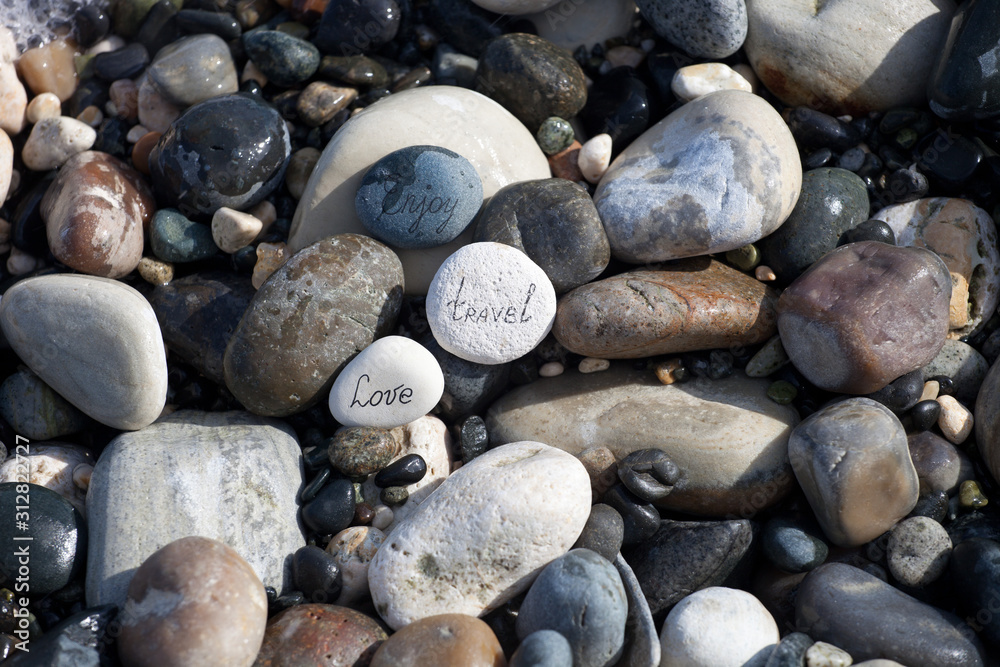 Words on pebble stones – motivational concept slogan – words love, travel, enjoy Words on pebble stones – motivational concept slogan – words love, travel, enjoy