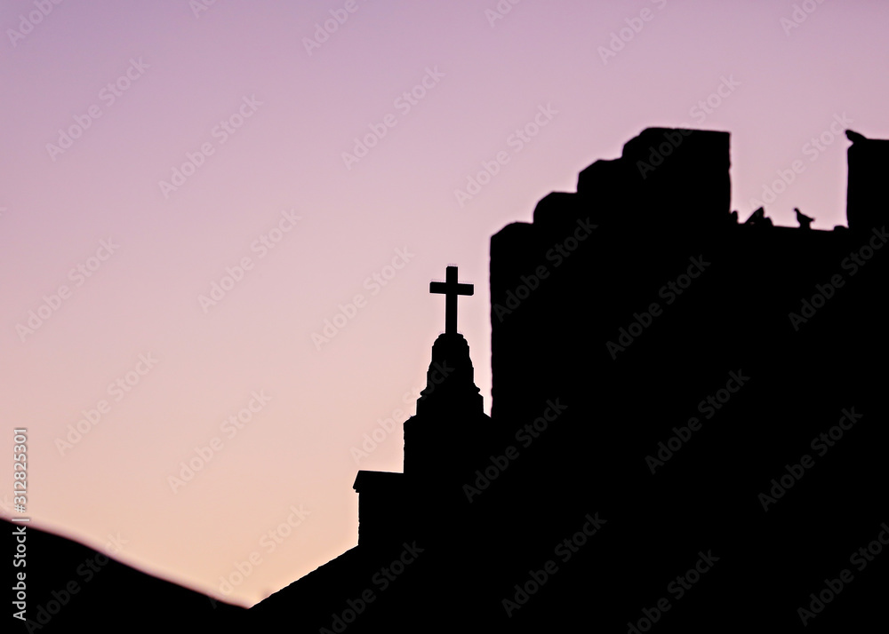 Silhouette of a Christian cross on a church at sunset. 