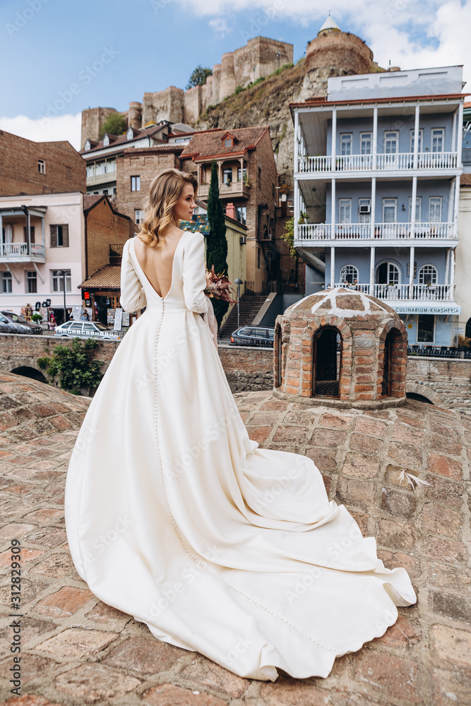 Obraz premium incredibly charming bride poses for a photo in a sophisticated wedding dress walking along the pretty streets of the old Georgian city of Tbilisi