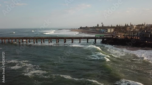 4K aerial drone video of Namibian Atlantic coastline, Swakopmund vintage buildings, town panorama, beach, old Jetty pier, landscape with ocean background of holiday resort at Namibia's west coast