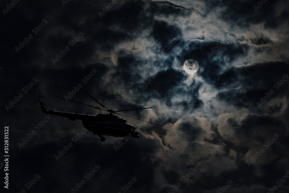 Helicopter on full moon background, hidden flight at night. Silhouette