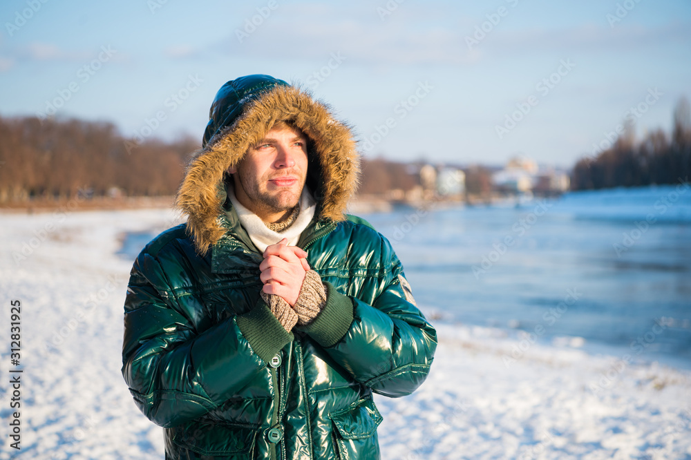 exploring nature. place for thoughts. cold and loneliness. male in down coat  with fur hood. feel warm and comfortable. guy green puffer coat. man enjoy  winter landscape. nature is beautiful Stock Photo