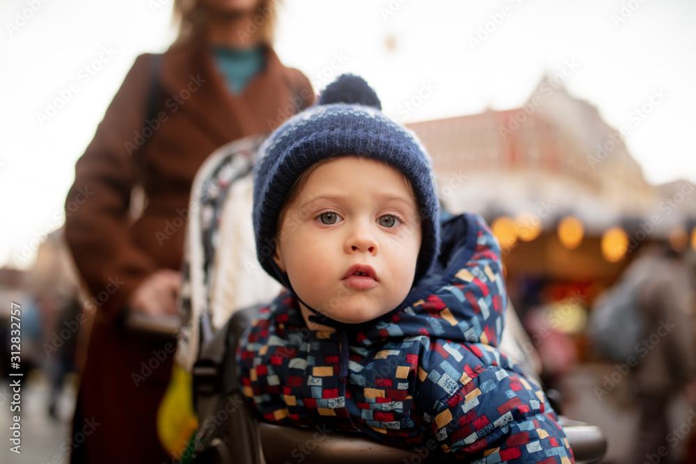 Littl boy sitting in a stroller and looking in camera Littl boy sitting in a stroller and looking in camera