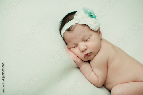 Sweet newborn infant baby girl laying on a cream colored neutral background