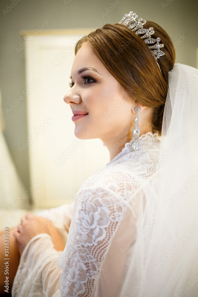 The bride in a white coat on the bed in a wedding morning The bride in a white coat on the bed in a wedding morning