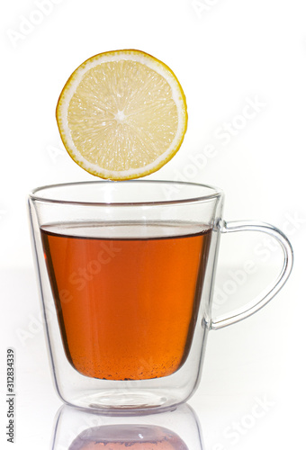 Tea with lemon in a glass thermo cup on a white background.