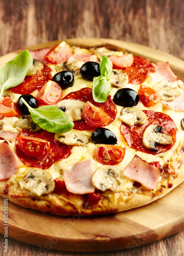 Pizza with ham, salami, champignon mushrooms, cherry tomatoes, black olives and fresh basil. 