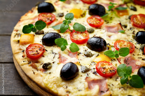 Pizza with ham, mozzarella cheese, cherry tomatoes, black olives and fresh oregano.