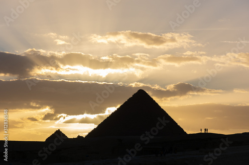 Silhouette of Pyramid of Menkaure and several people in front of sunset in Giza