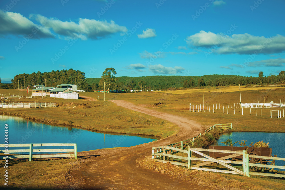 Pretty farm with fences, livestock sheds and lake