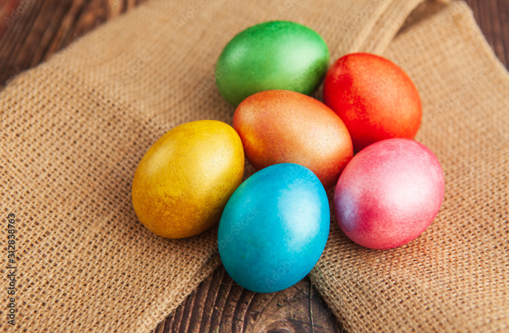 Colored easter eggs on a wooden background on burlap, top view