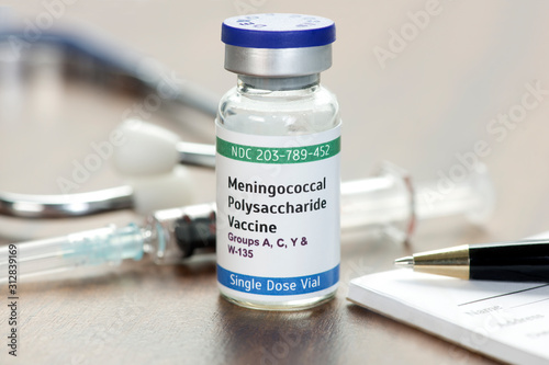 Meningococcal Polysaccharide Vaccine Vial on physician's desk with syringe, stethoscope, and prescription pad