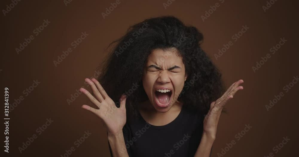 Portrait of african american girl shouting against the brown wall background