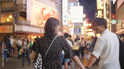 Asian couple Romantic walk through Neon Lights of Osaka Nightlife. photo