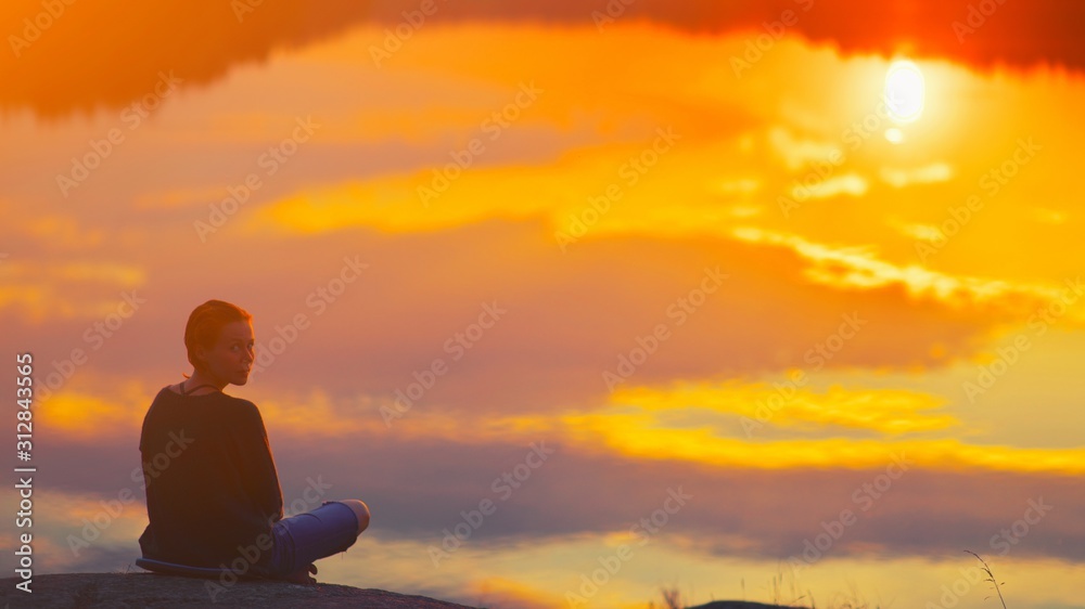 Beautiful woman sits in a pose of a lotus on high place with amazing view of the lake sunset practice yoga meditation Kundalini energy mindset intuition prana. Solitude harmony mental freedom concept