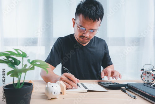 Businessman using calculators and notebooks to plan home payment installments.The concept of home installments, reducing principal and reducing interest.Asian man planning financial.