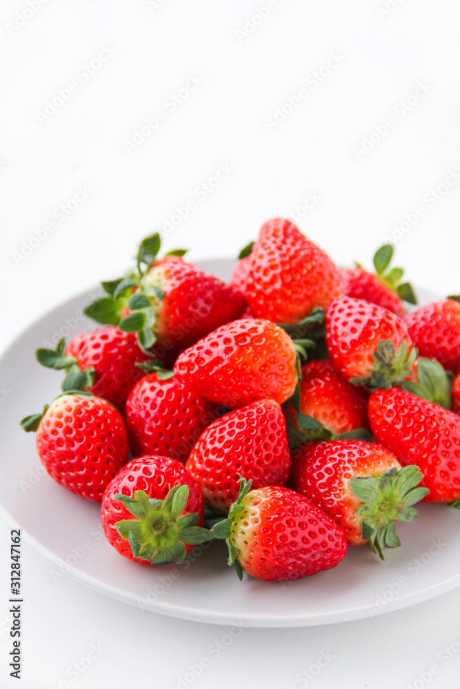 Fresh strawberries on a light grey plate, on a white background Fresh strawberries on a light grey plate, on a white background