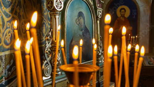 Canvastavla Blurred wax burning candles in an orthodox church on the icon background