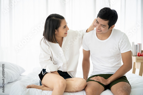 Funny and romantic Asian couple' portrait in bedroom with natural light from window, concept of relationship between husband and wife and being a family.