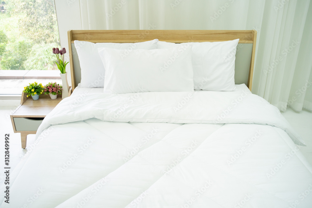 Bedroom decorated in minimal style, photograph of white pillows and wooden bed in bedroom with natural light from window. Bedroom decorated in minimal style, photograph of white pillows and wooden bed in bedroom with natural light from window.