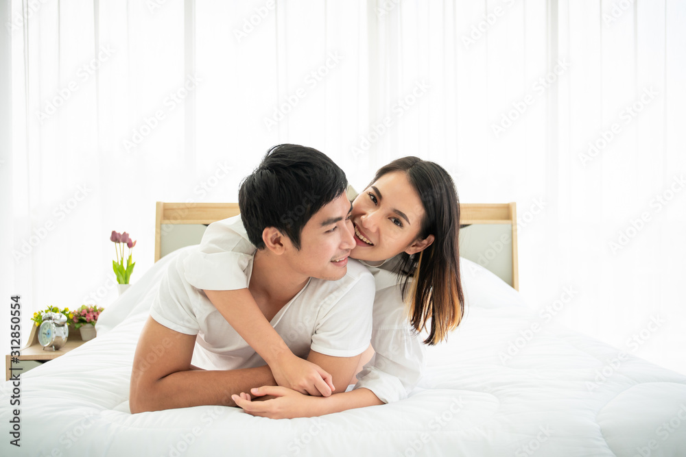Beautiful Asian couple laying and talking together on the bed. Couple relationship concept.