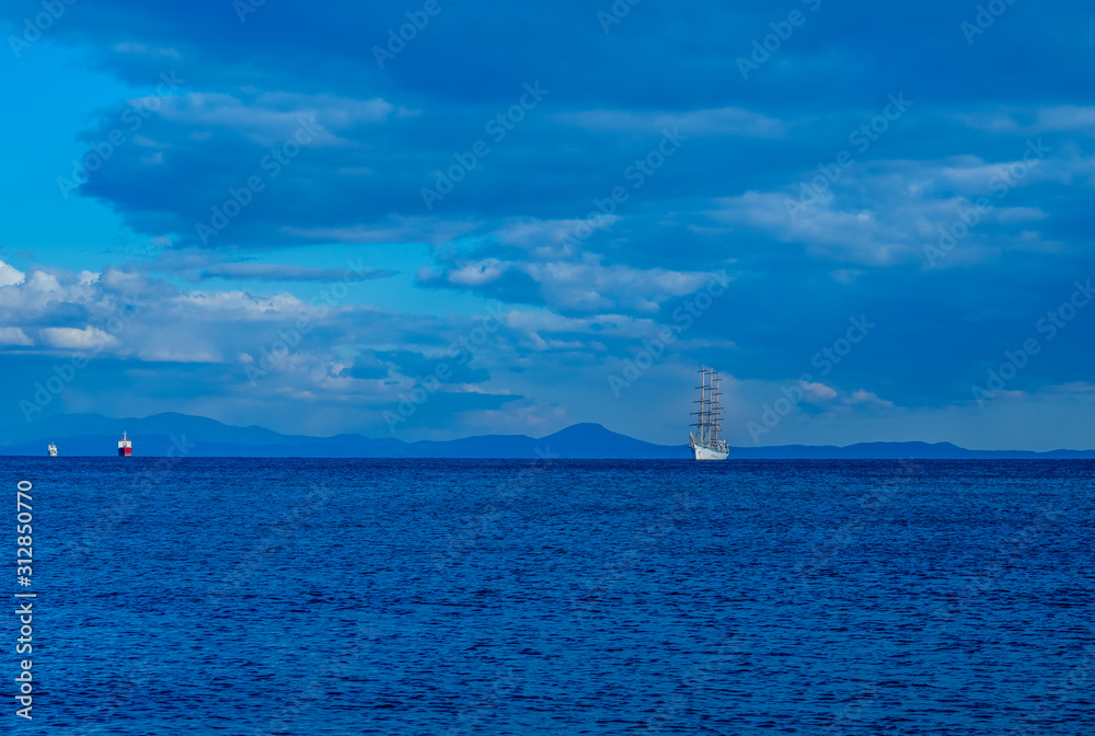 Seascape with a beautiful sailboat on the horizon.