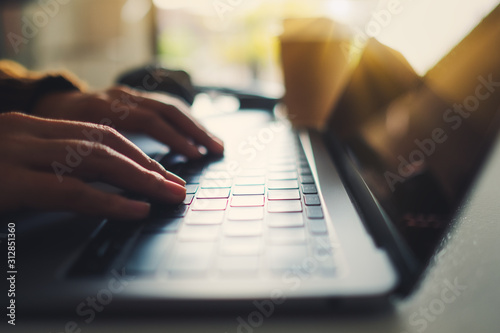 Closeup image of a woman's hands working and typing on laptop computer on the table