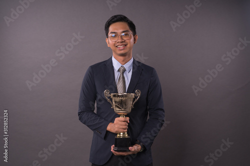 Happy young male intrepreneur or business man holding his gold trophy.Studio shot. photo