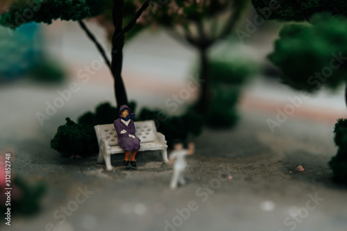 close up of small people sitting in chairs in the park.