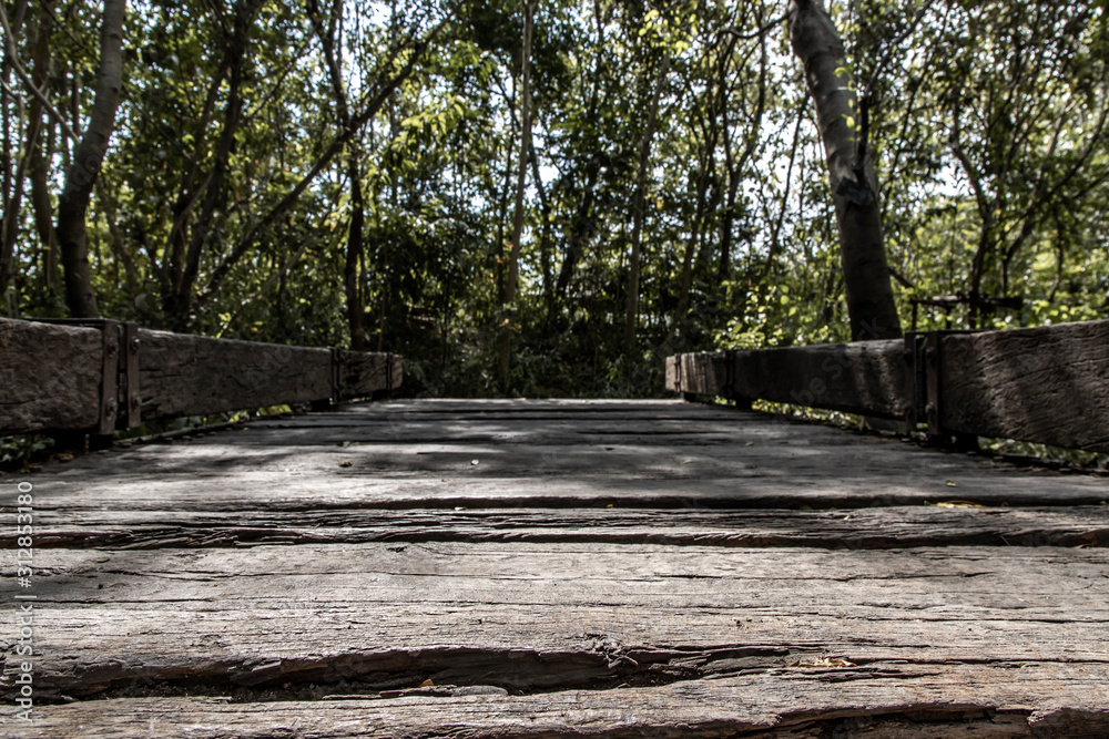 Old wooden walkway through the nature park, That has Sun rays shining through. Beautiful background. Old wooden walkway through the nature park, That has Sun rays shining through. Beautiful background.