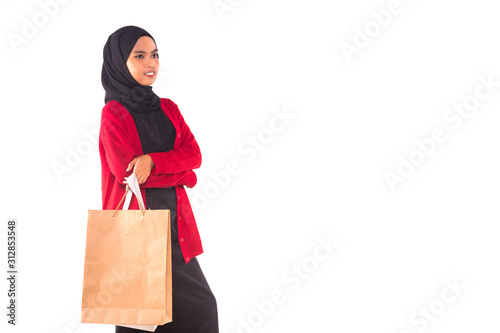 Happy young Muslim girl holding shopping bags isolated over white background.