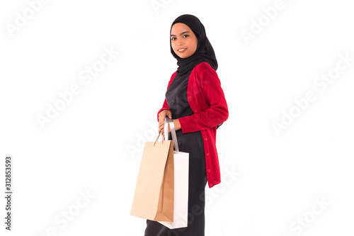 Happy young Muslim girl holding shopping bags isolated over white background.