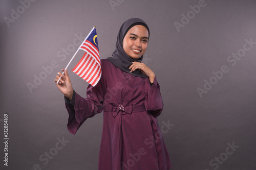 Happy Malaysian girl holding Malaysia Flag.Independence Day and patriotic concept.Studio shot.