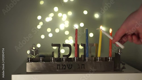 Hands using the shamus candle to light the hannukah candles, representing the miracle of light in the Jewish religion photo